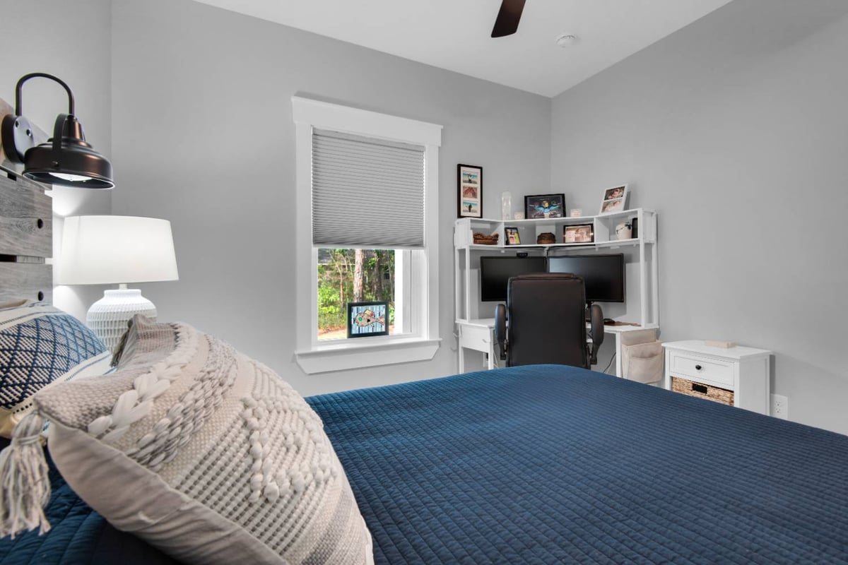 bedroom with blue bedding and desk area in Pensacola custom home by EZ Modern Homes The Lafon-optimized