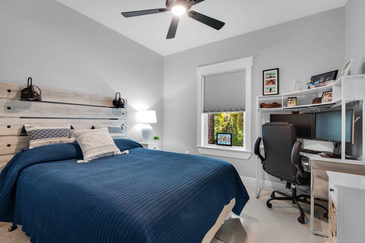 bedroom with blue bedspread and desk workspace in Pensacola custom home by EZ Modern Homes The Lafon-optimized