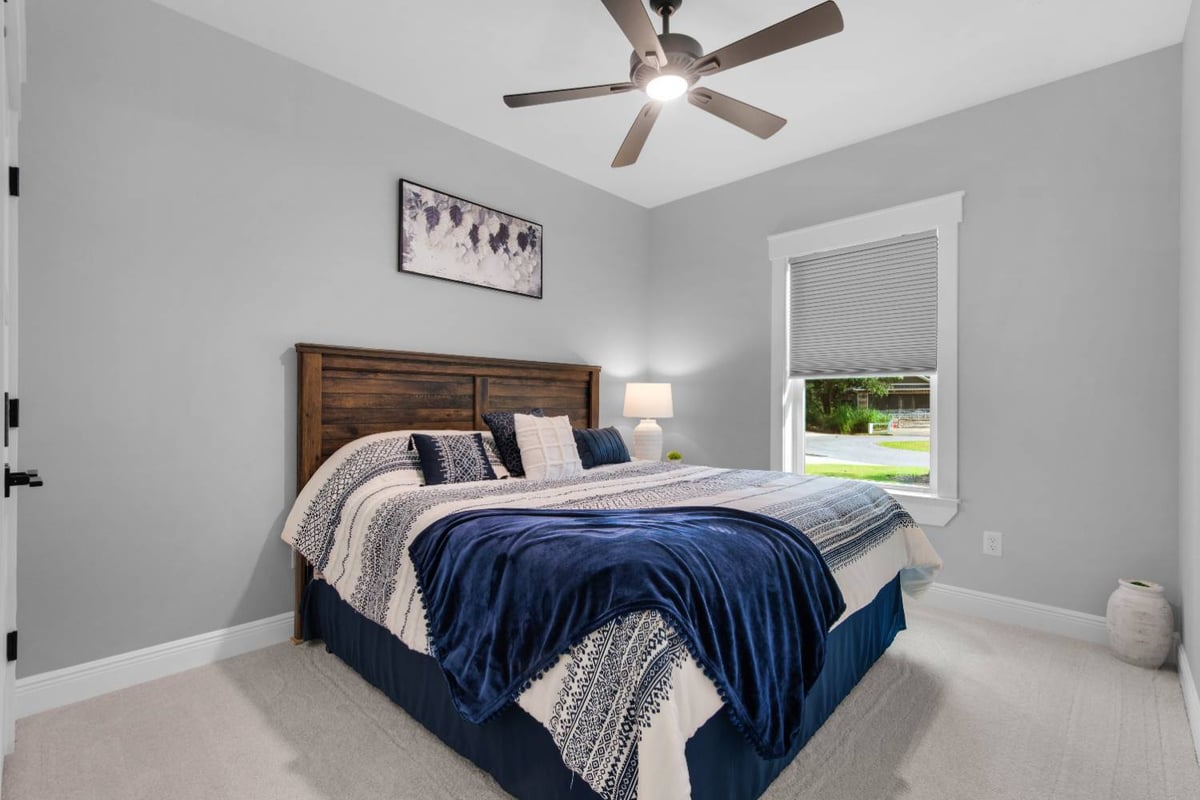 cozy bedroom with wood headboard and blue bedding in Pensacola custom home by EZ Modern Homes The Lafon-optimized