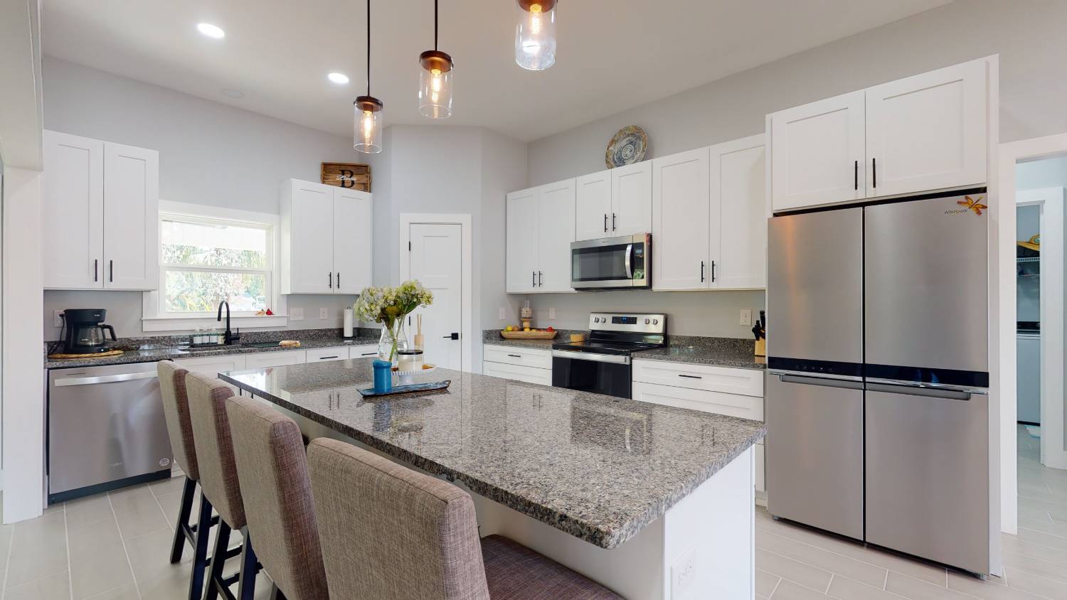 bright kitchen with island seating and stainless steel fridge in The Lafon custom home by EZ Modern Homes in Pensacola, FL-optimized