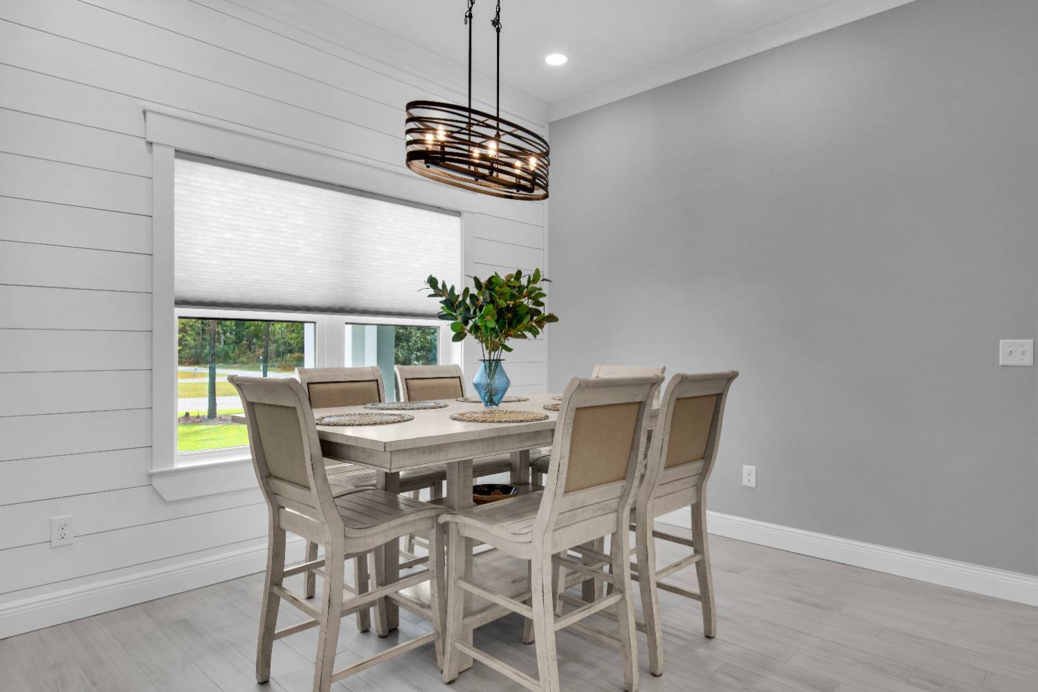 Dining area with window view and modern light fixture in The Lafon custom home by EZ Modern Homes Pensacola, FL-optimized