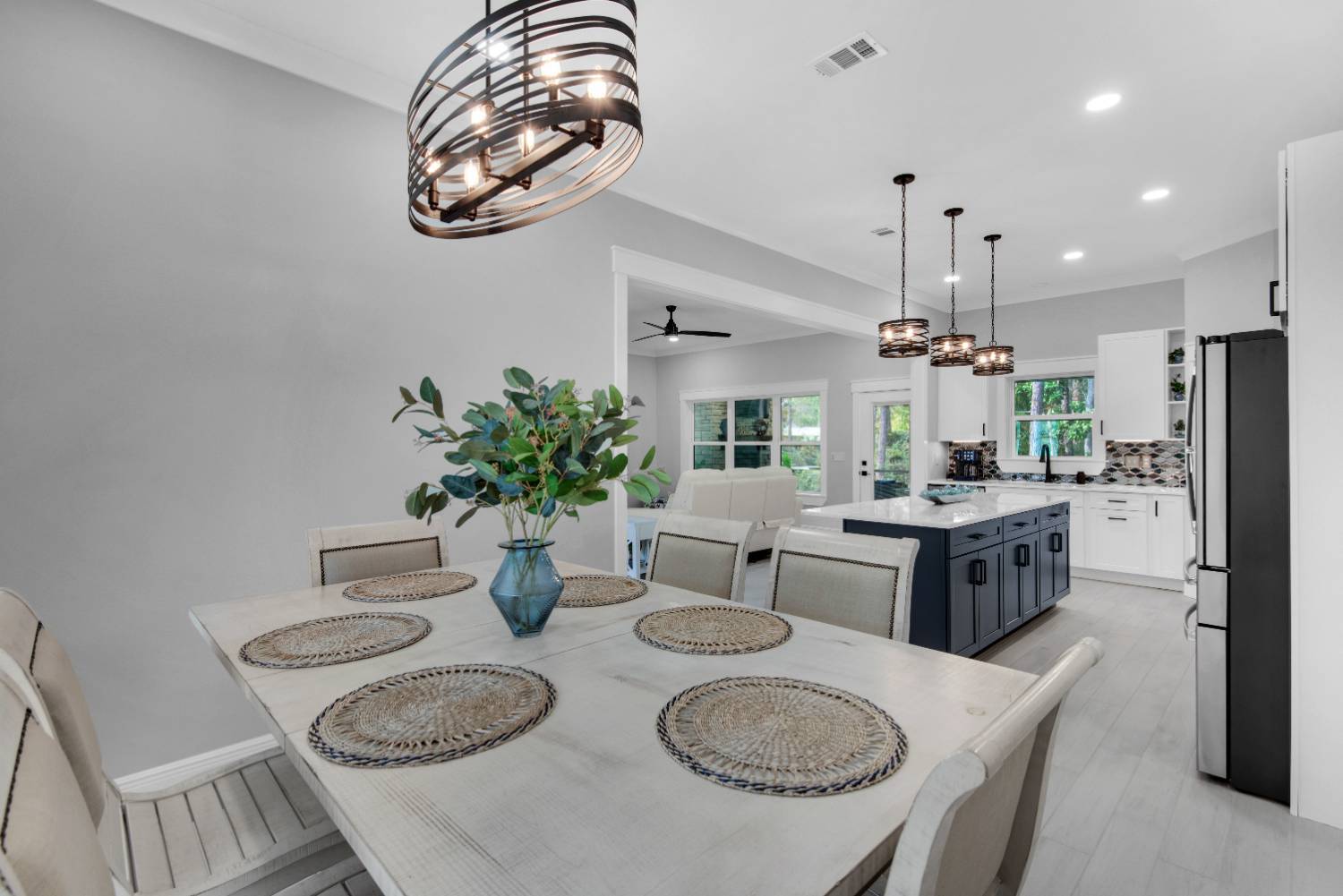 Open dining and kitchen layout with island in The Lafon custom home by EZ Modern Homes Pensacola, FL-optimized